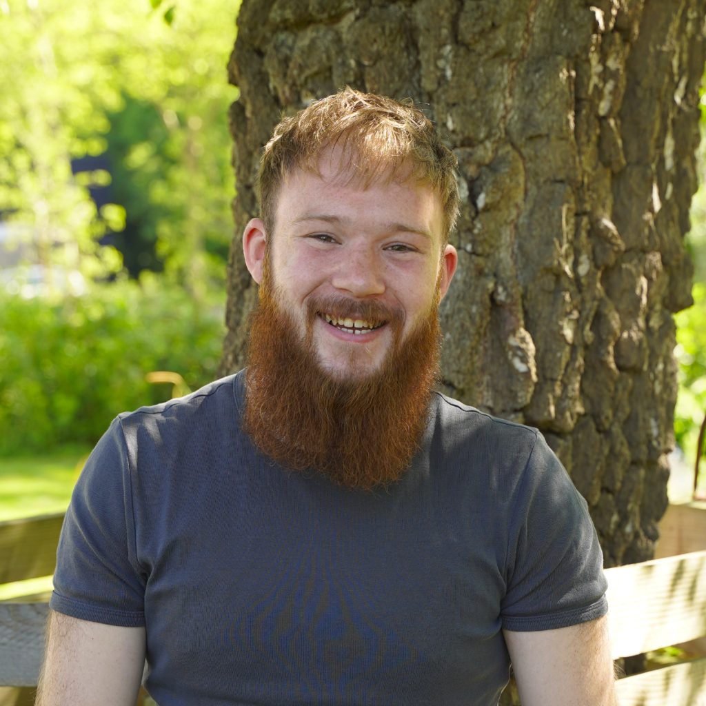 Liam buiten in het groen, lachend voor de camera